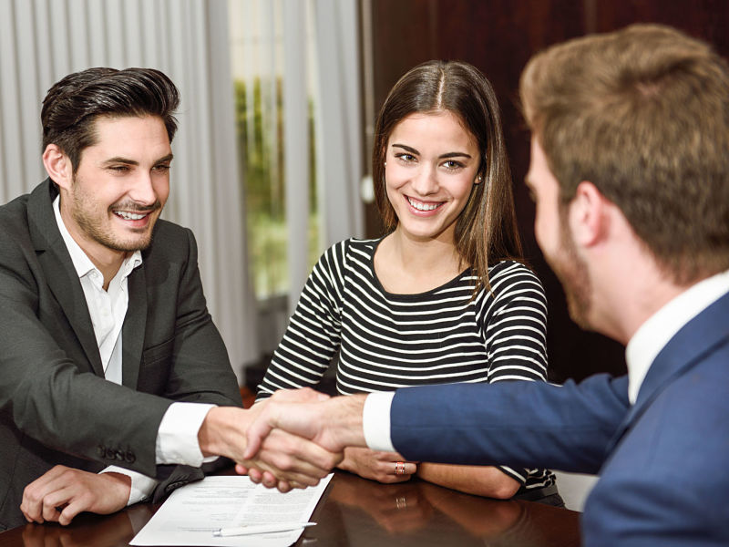 38383072 - smiling young couple shaking hands with an insurance agent or investment adviser